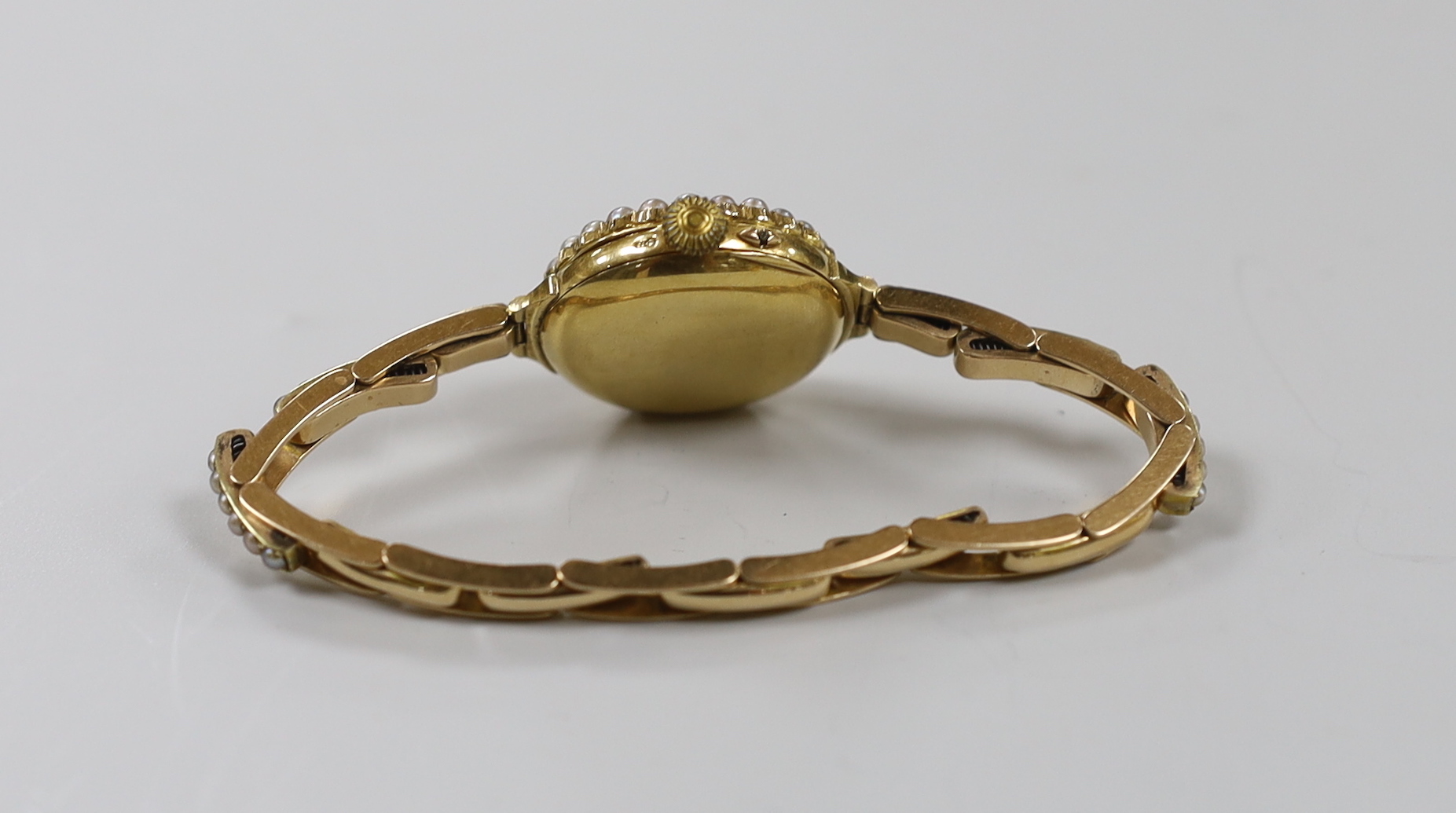 A lady's early 20th century 18ct gold and seed pearl set manual wind wrist watch, on a flexible 15ct and seed pearl set bracelet